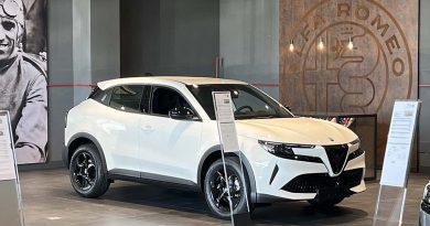 Alfa Romeo Junior ibrida esposta in concessionaria, versione bianca con cerchi in lega da 17 pollici, design compatto e frontale con Scudetto Leggenda.